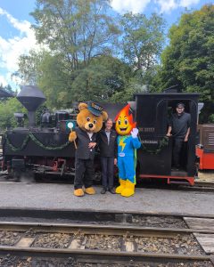Der Geschäftsführer mit zwei Maskottchen vor einer Dampflok